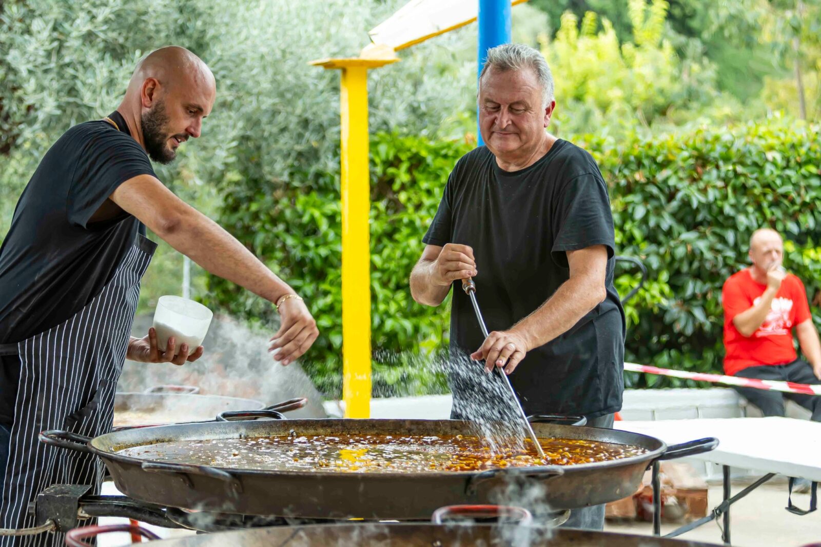 Professional chef preparing a giant traditional Spanish paella over an open fire at La Tomatina festival in Buñol, Valencia.