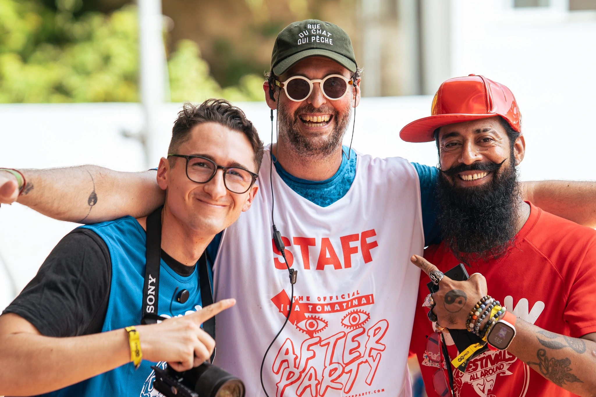 Smiling staff members wearing "Official La Tomatina After Party" t-shirts posing during the celebration in Spain.